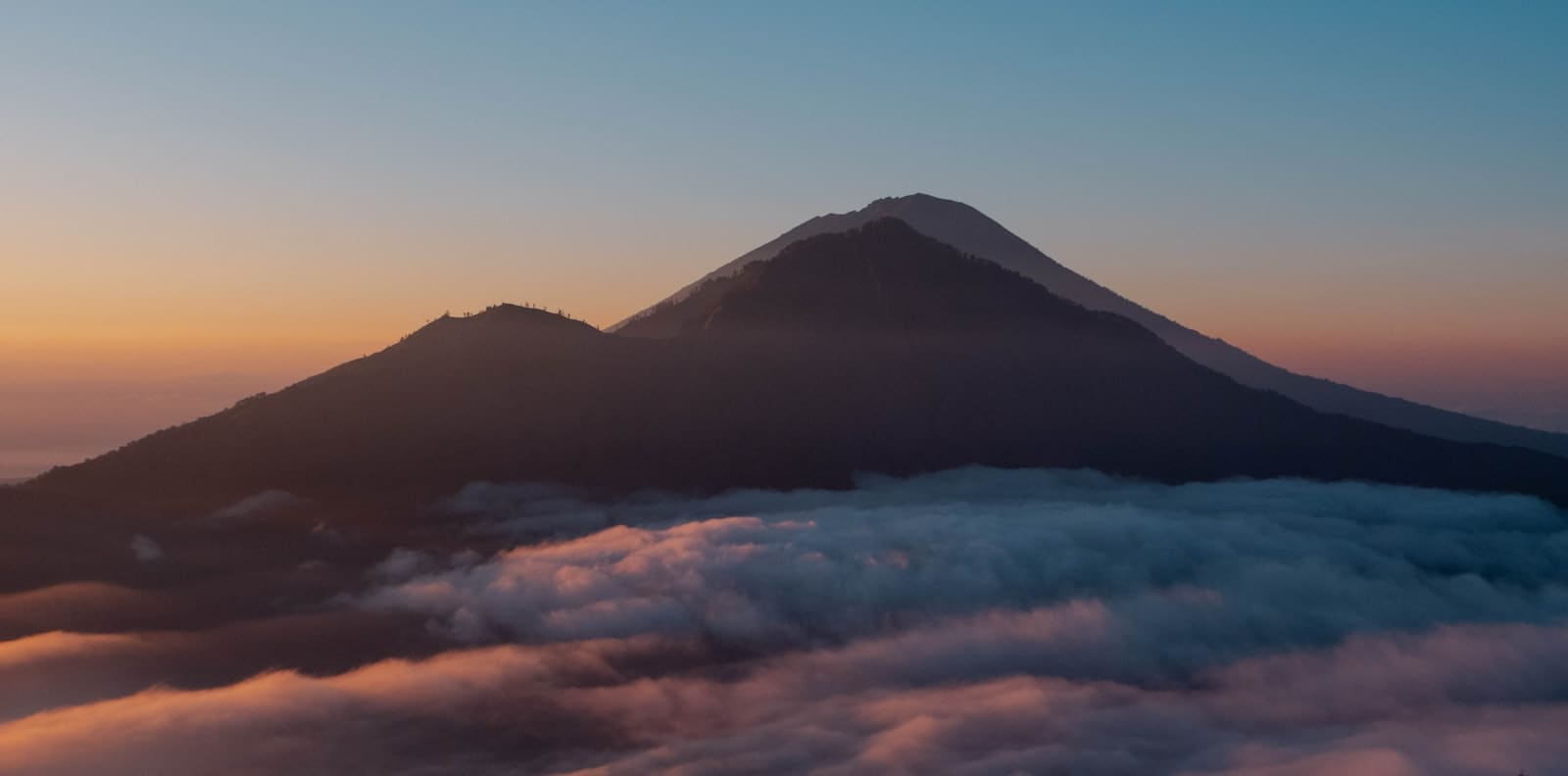 A cloud-wrapped volcanic cone at last light.