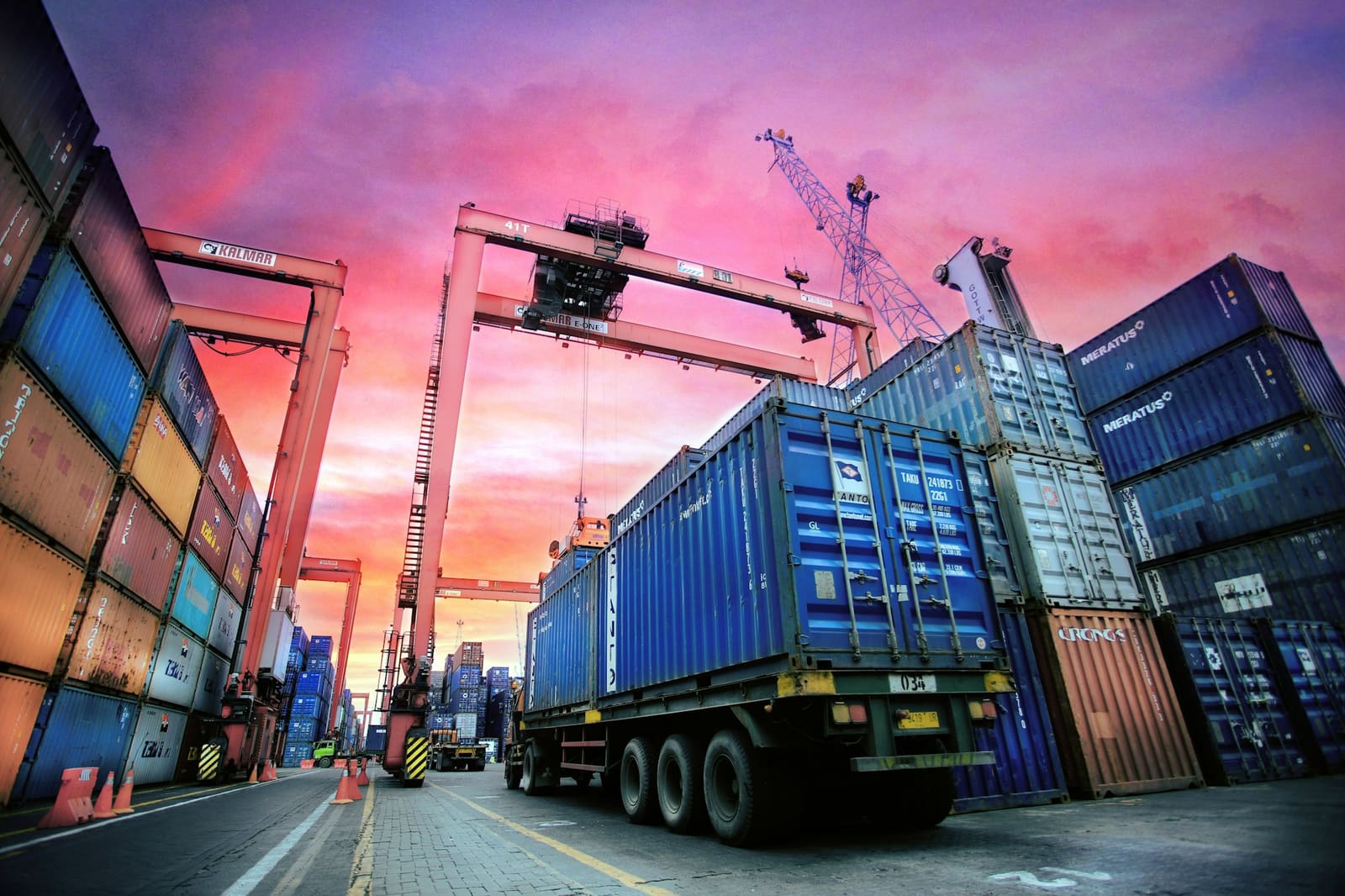 Stacked shipping containers under low sun at a working port.