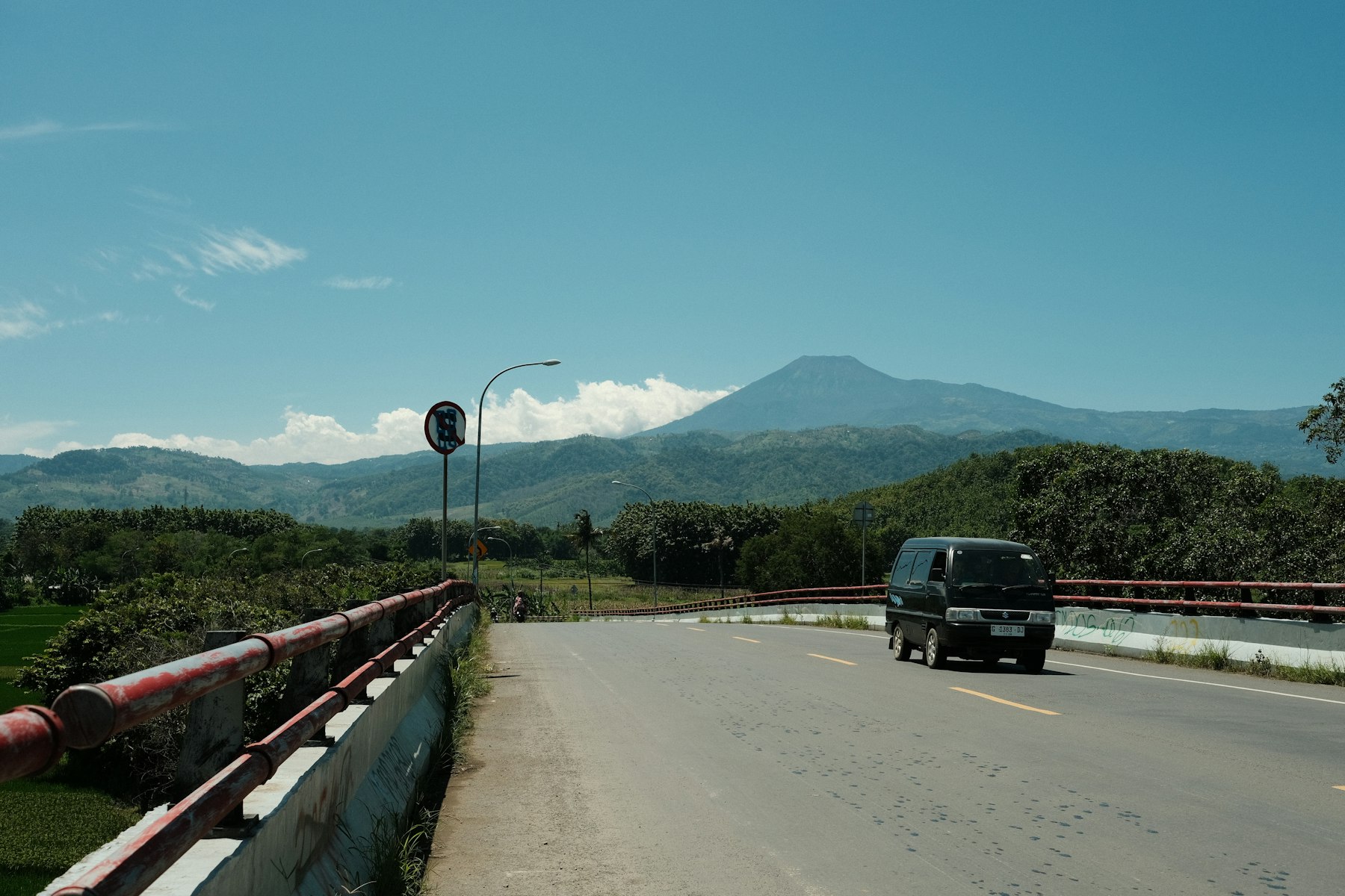 A truck on a mountain road cut into a green hillside.